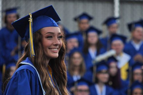A graduate in cap and gown smiling